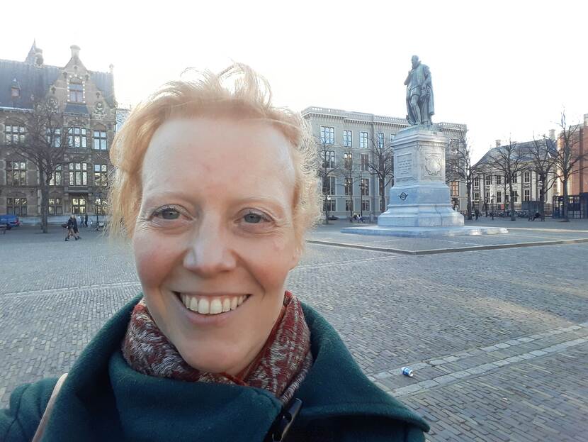 Jacqueline de Graauw op het Plein in Den Haag met op de achtergrond het standbeeld van Willem van Oranje en gebouw K van de Tweede Kamer