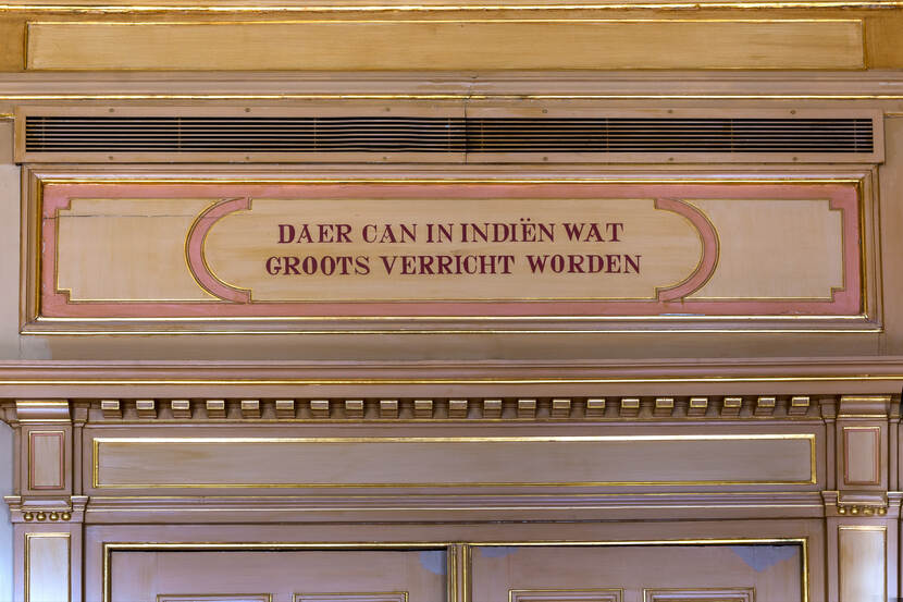 Regentenkamer in voormalig ministerie van Koloniën, detailopname van betimmering boven porte-brisée en bovendeurstuk met tekst "daer kan in indiën iets groots verricht worden"