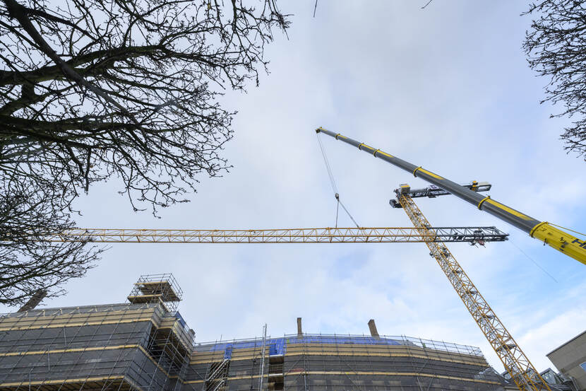 De 70 meter lange giek van de torenkraan op de Hofplaats wordt met een mobiele kraan omhoog gehesen