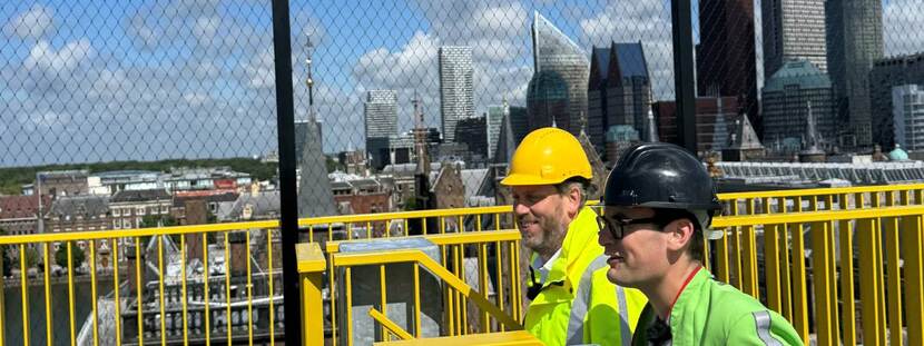 Bauke van der Goot en Splinter Chabot op het Uitzichtpunt Binnenhof met op de achtergrond de skyline van Den Haag