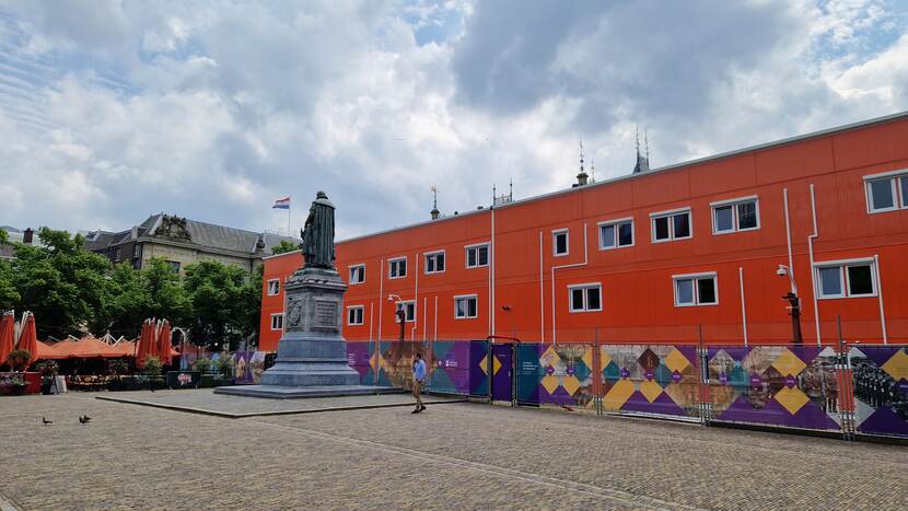 De oranje bouwkeet op het Plein met de tijdelijke bouwhekken en het standbeeld van Willem van Oranje